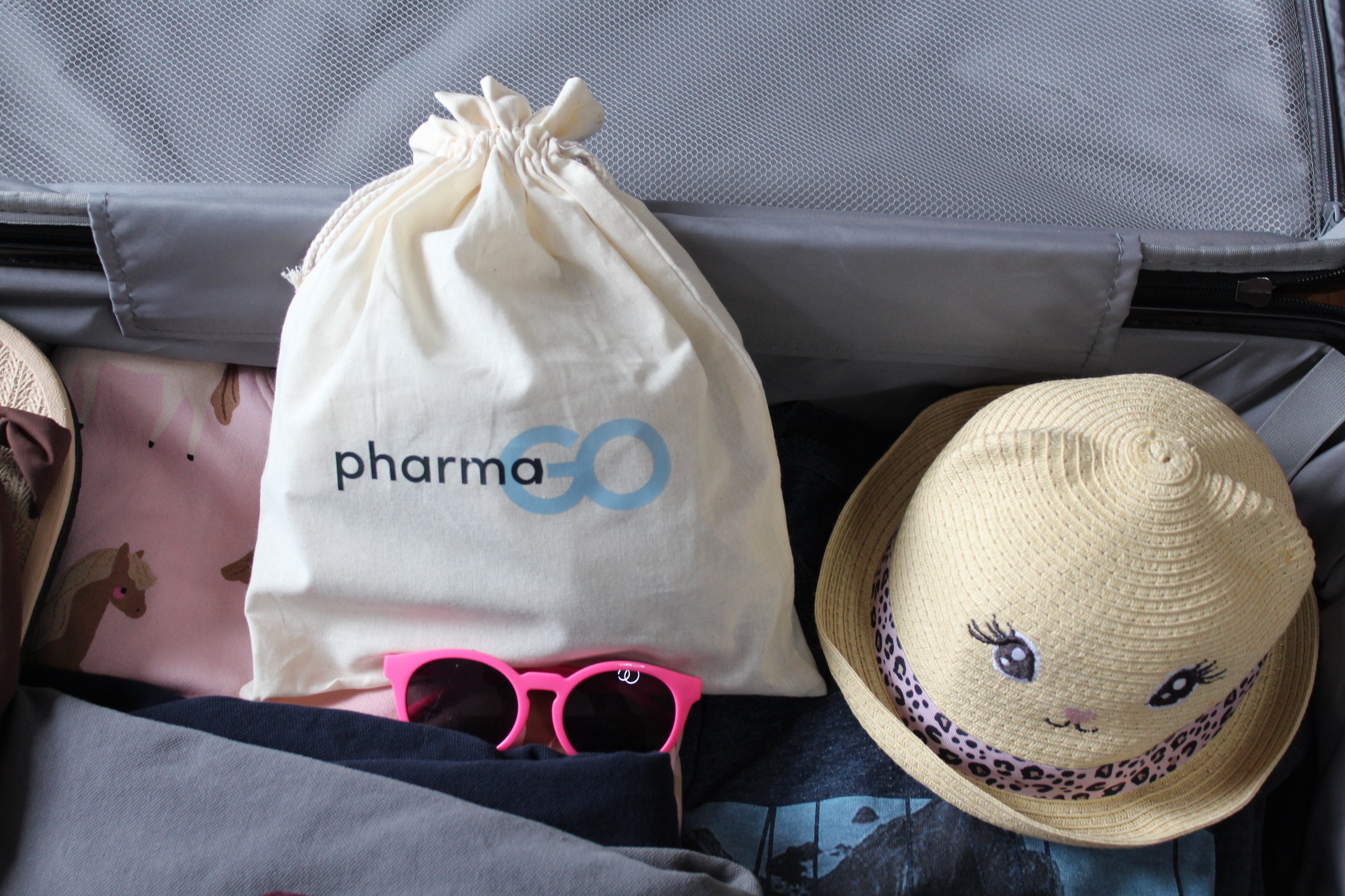 Reiseapotheke von pharmaGo mit Beutel, Kindersonnenhut und Sonnenbrille – Packtipps für Familien